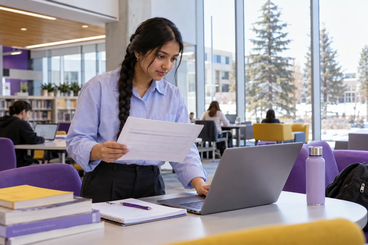Young Nepali woman with a long braid comparing a personal study budget worksheet and university tuition information on a laptop for Canada study planning
