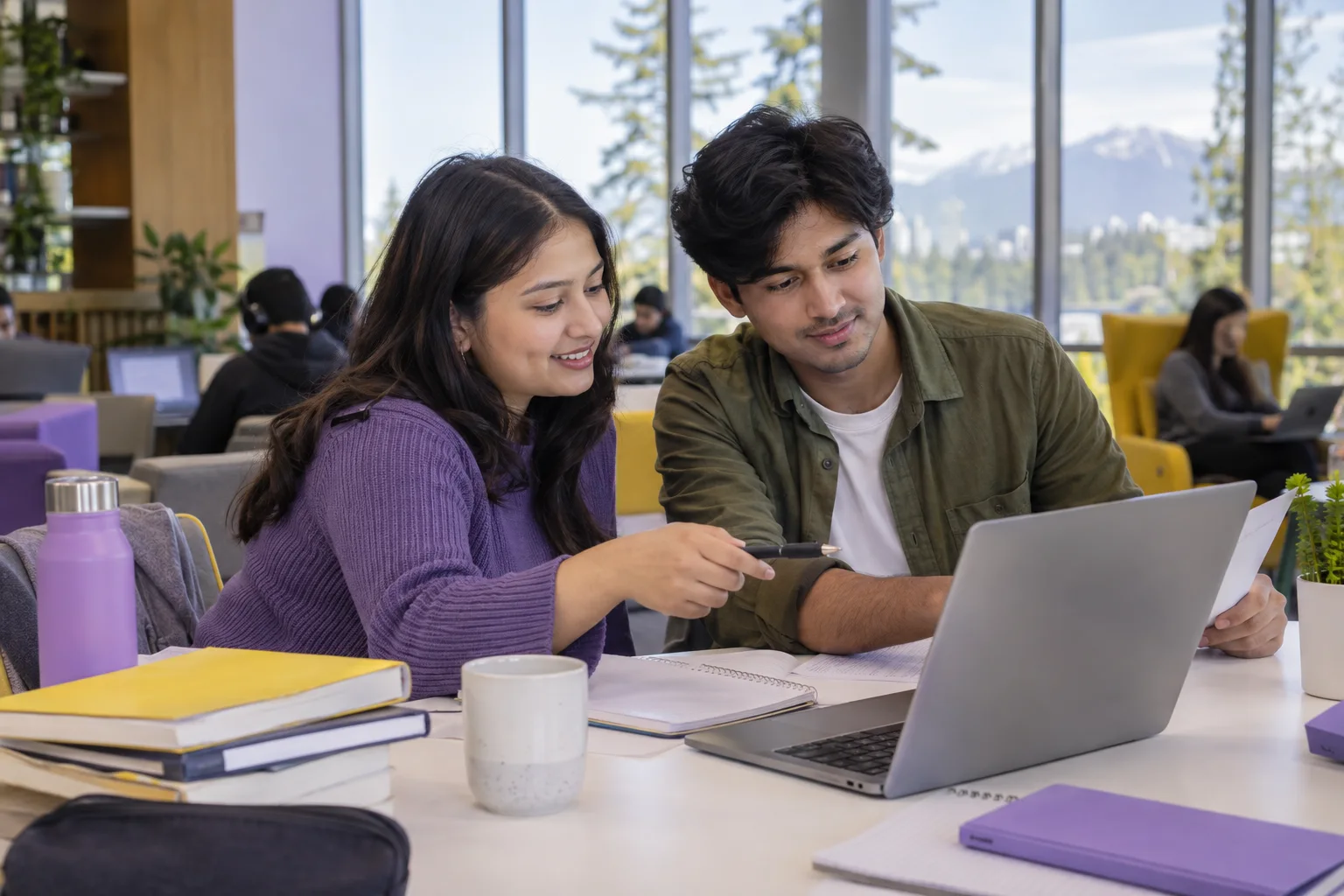 Two Nepali students, one woman and one man comparing a personal study budget worksheet and university tuition information on a laptop for Canada study planning