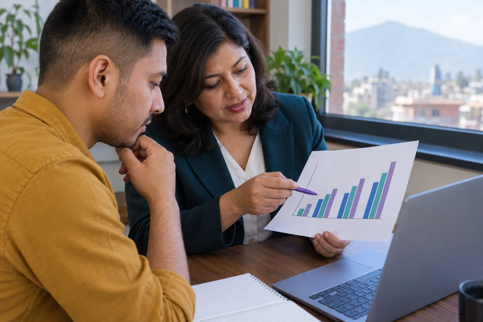 GMAT learner and mentor reviewing a printed bar chart beside a laptop