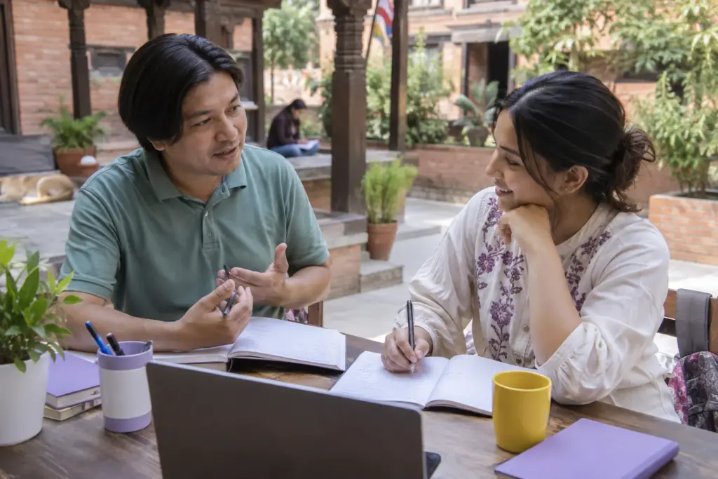 IELTS Speaking learner practises a conversation with a tutor in a Kathmandu courtyard